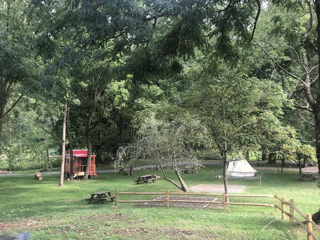 A distant view of the campground featuring picknick tables and a caboose