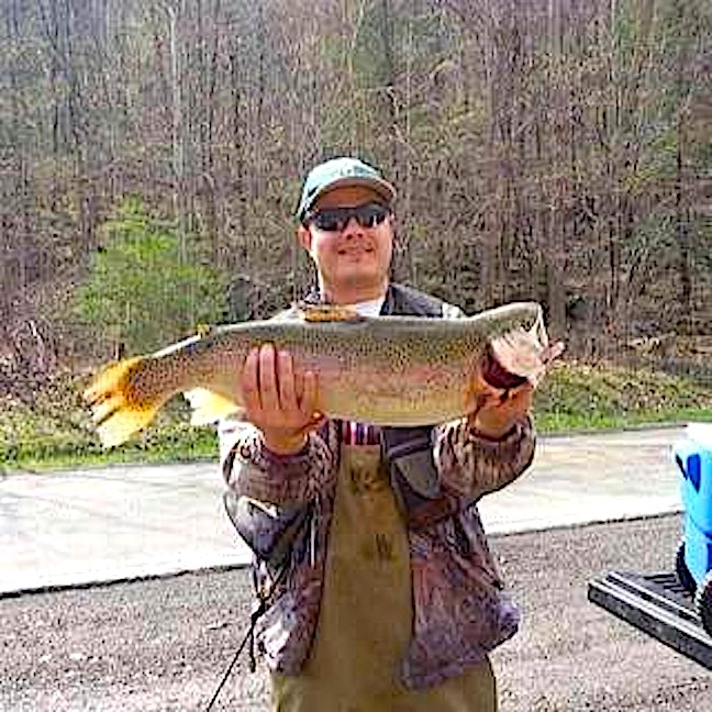 A man wearing sunglasses holding a large fish